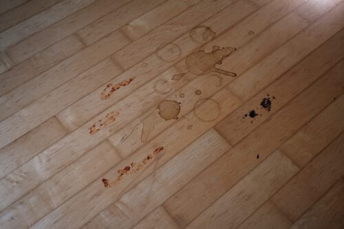 Coffee, tomato sauce, and chocolate cake stains on a hard wood floor.