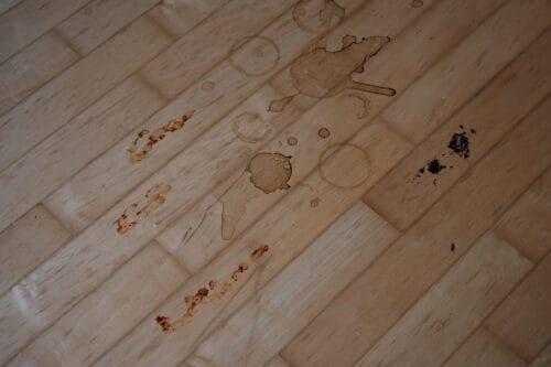 Coffee, tomato sauce, and chocolate cake stains on a hard wood floor.