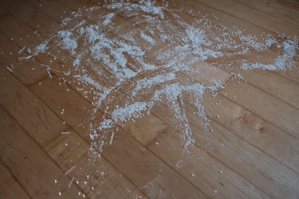 Rice, flour, coarse brown sugar, and broken up noodles on a hard wood floor