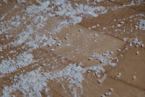 Rice, flour, coarse brown sugar, and broken up noodles on a hard wood floor