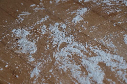 Rice, flour, coarse brown sugar, and broken up noodles on a hard wood floor