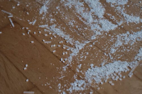 Rice, flour, coarse brown sugar, and broken up noodles on a hard wood floor