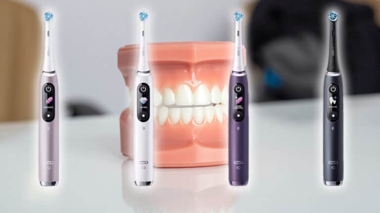 Four Oral-B iO electric toothbrushes with different settings displayed on their handles are arranged on a surface. In the centre, there is a dental model showing a set of pearly white teeth.