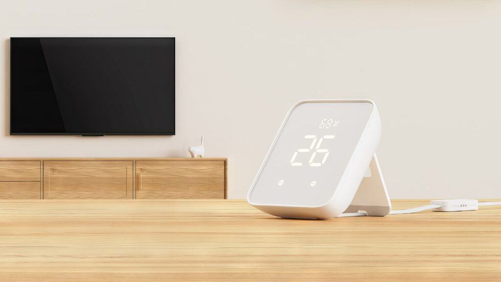 A render of the Matter-supporting SwitchBot Hub 2 on a wooden table. It prominently displays the temperature and humidity through built-in sensors.